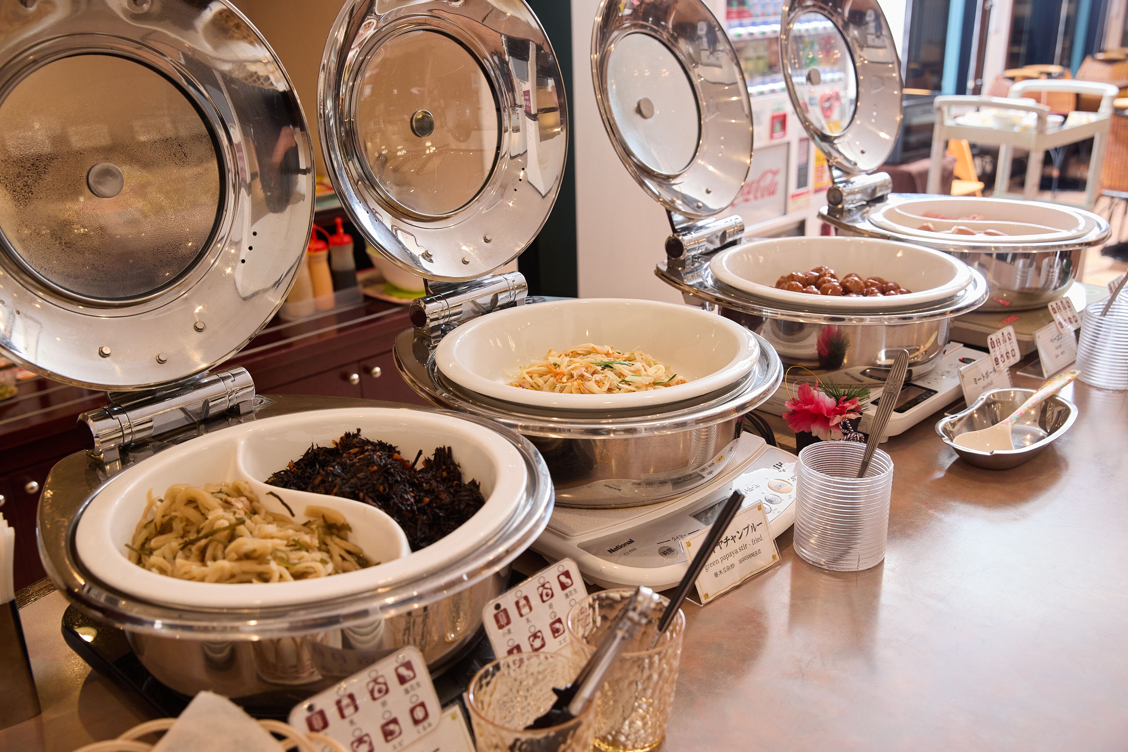 Un buffet proposant une variété de plats présentés dans des bols et des récipients, notamment des pâtes, des salades et d’autres mets.