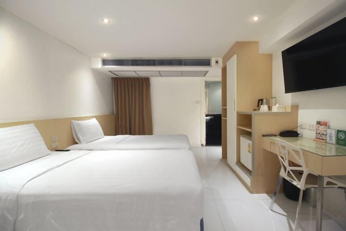 Een hotelkamer met twee bedden, een bureau, een televisie en een airconditioning.