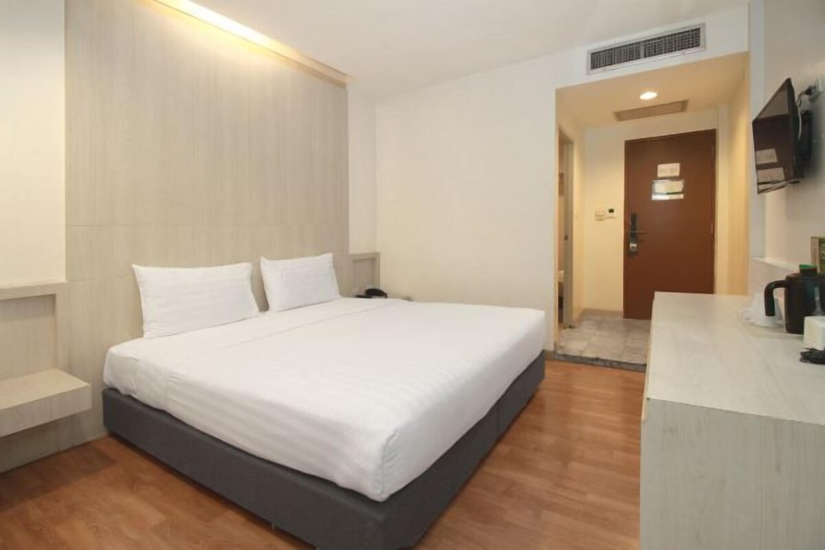 Een moderne hotelkamer met een groot bed, een nachtkastje, een ingebouwde televisie en een klein kitchenette.