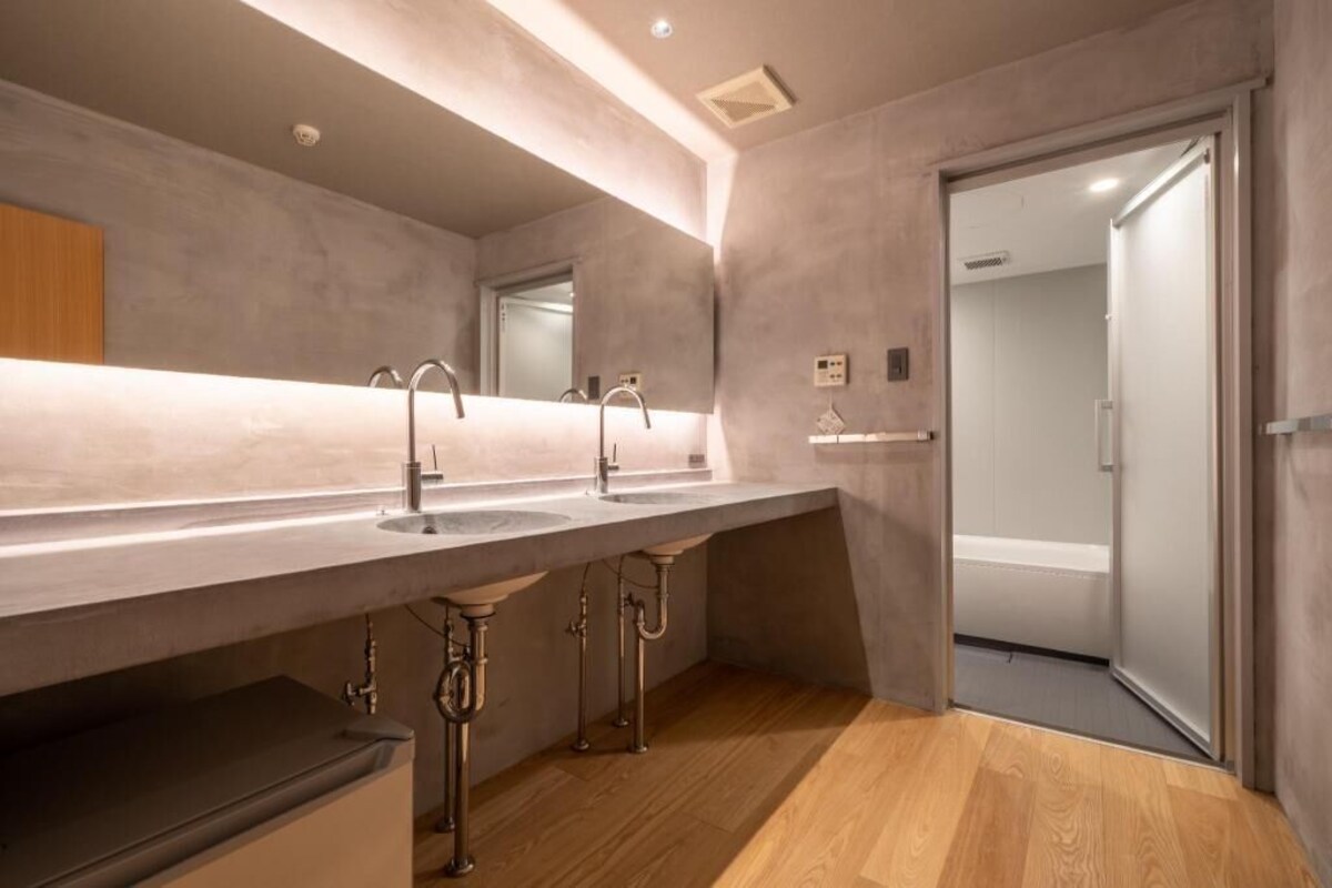 A modern bathroom with a large mirror, two sinks, and a shower area.