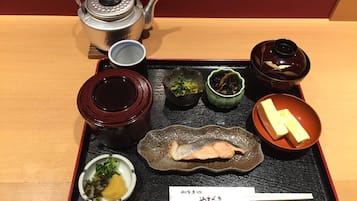 A tray with a teapot, cups, bowls of food, and a menu.