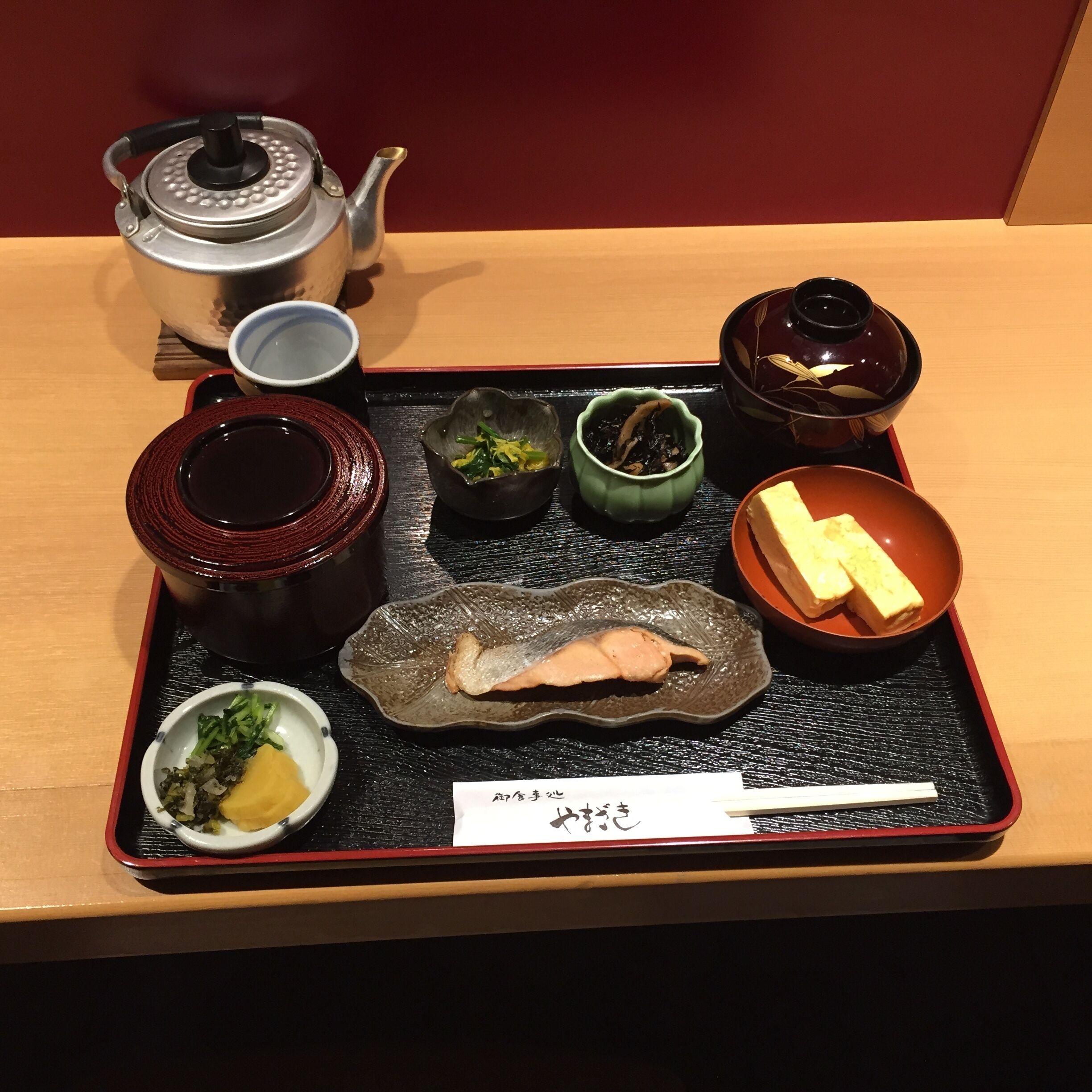 A tray with various Japanese dishes, including a pot, bowls, and a teapot.