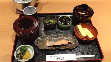 A tray with various Japanese dishes, including a pot, bowls, and a teapot.