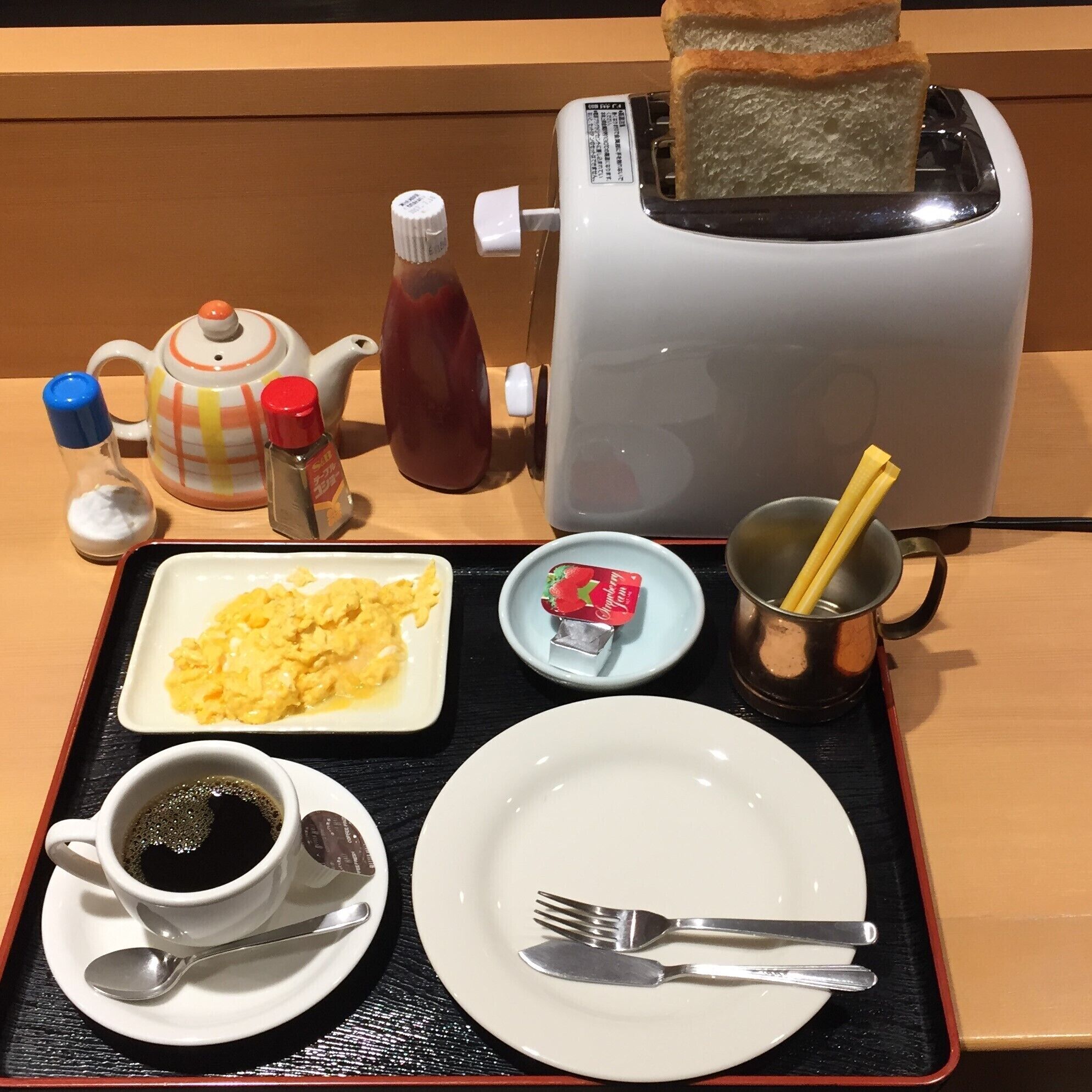A breakfast tray with scrambled eggs, toast, coffee, and tea.
