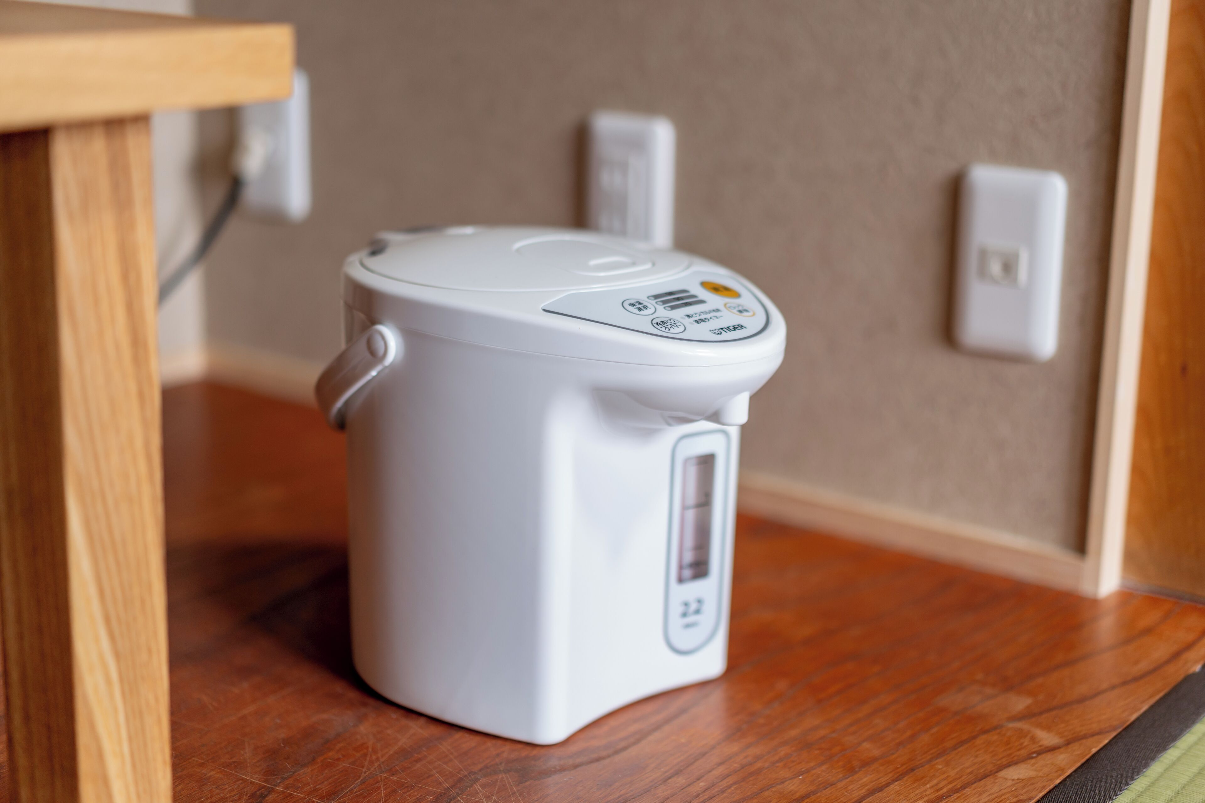 A white electric kettle on a wooden table with a digital display.