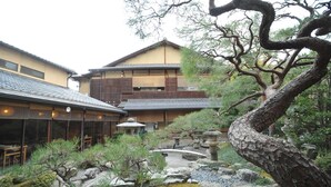 A traditional Japanese building with a garden featuring rocks, trees, and a stone lantern.