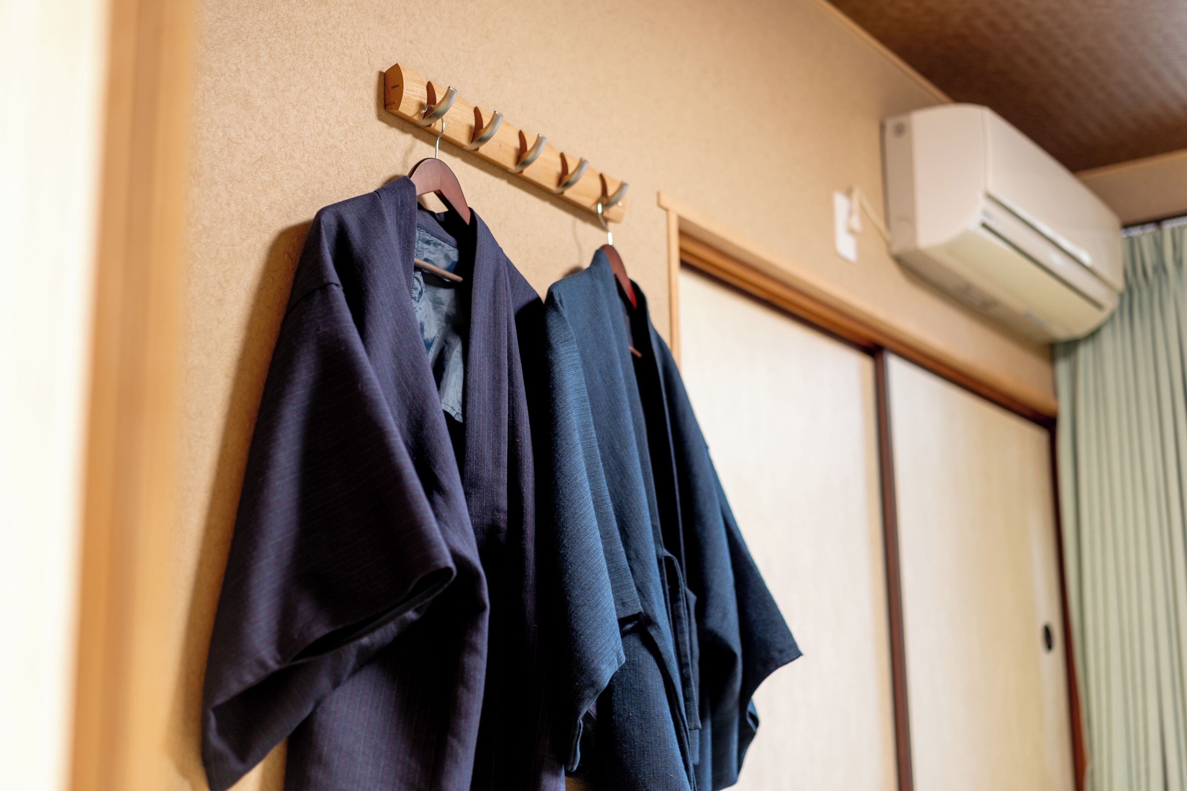 A wall-mounted coat rack with several dark-colored coats.