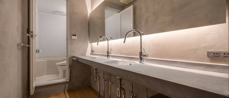 A modern bathroom with a large mirror, two sinks, and a shower.