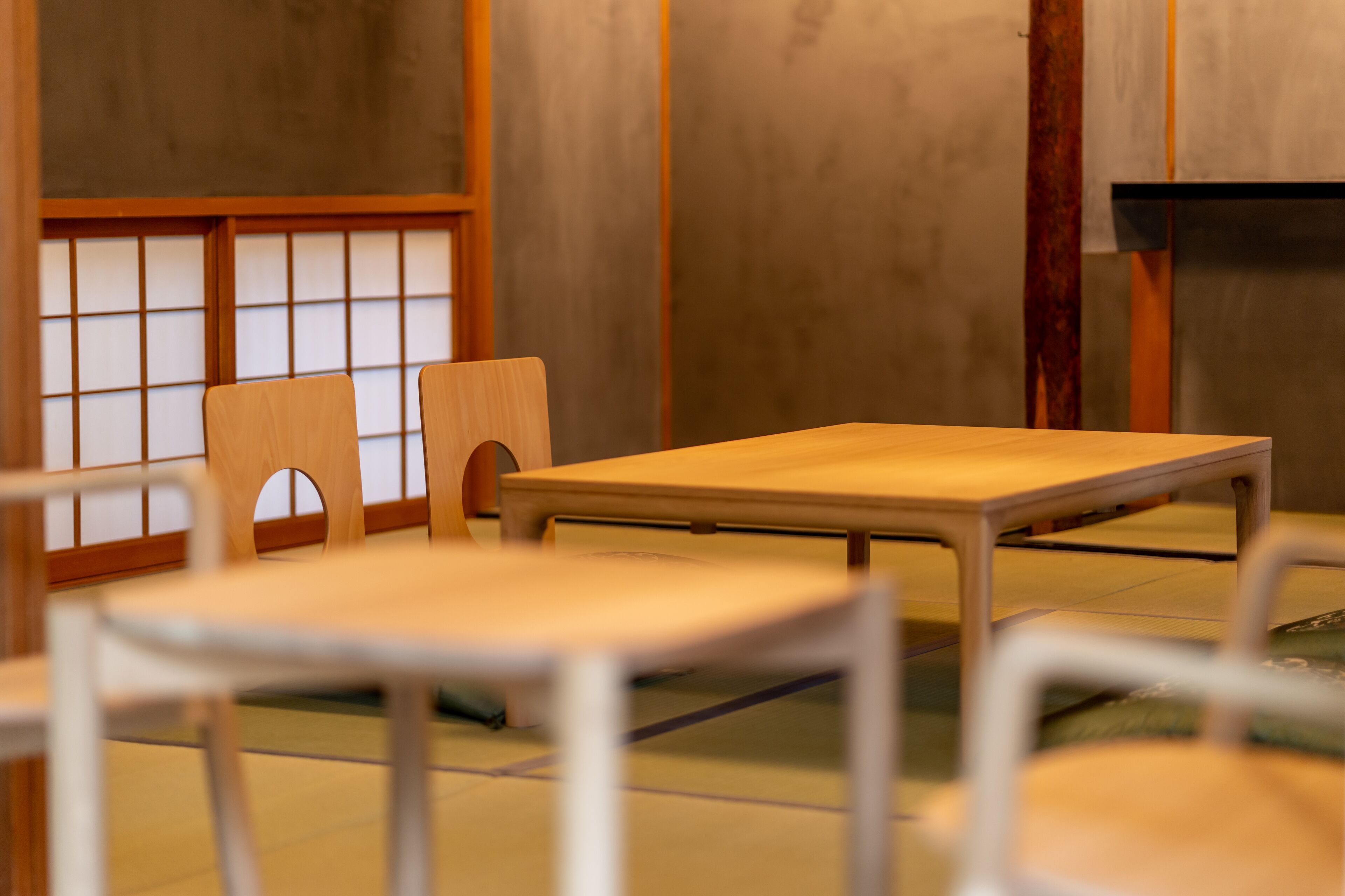 A traditional Japanese room with tatami flooring, a low wooden table, and a low wooden chair.