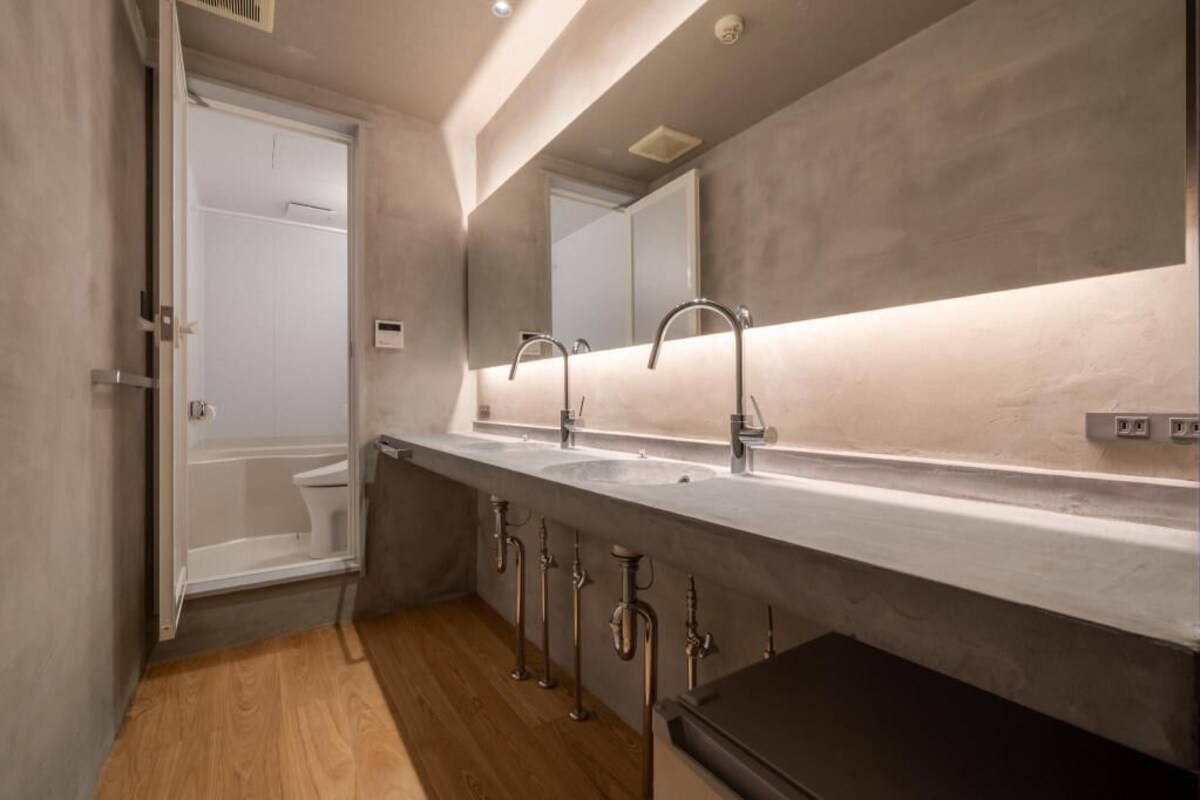 A modern bathroom with a large mirror, two sinks, and a shower.