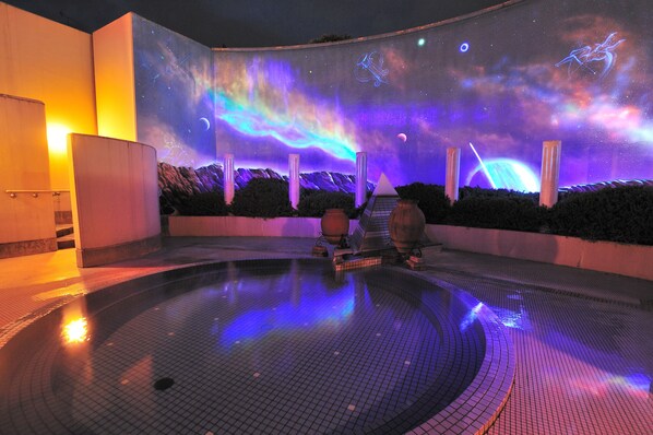 A pool area with a water feature and a large illuminated wall displaying a space-themed design. - Shisuitei (Numata)