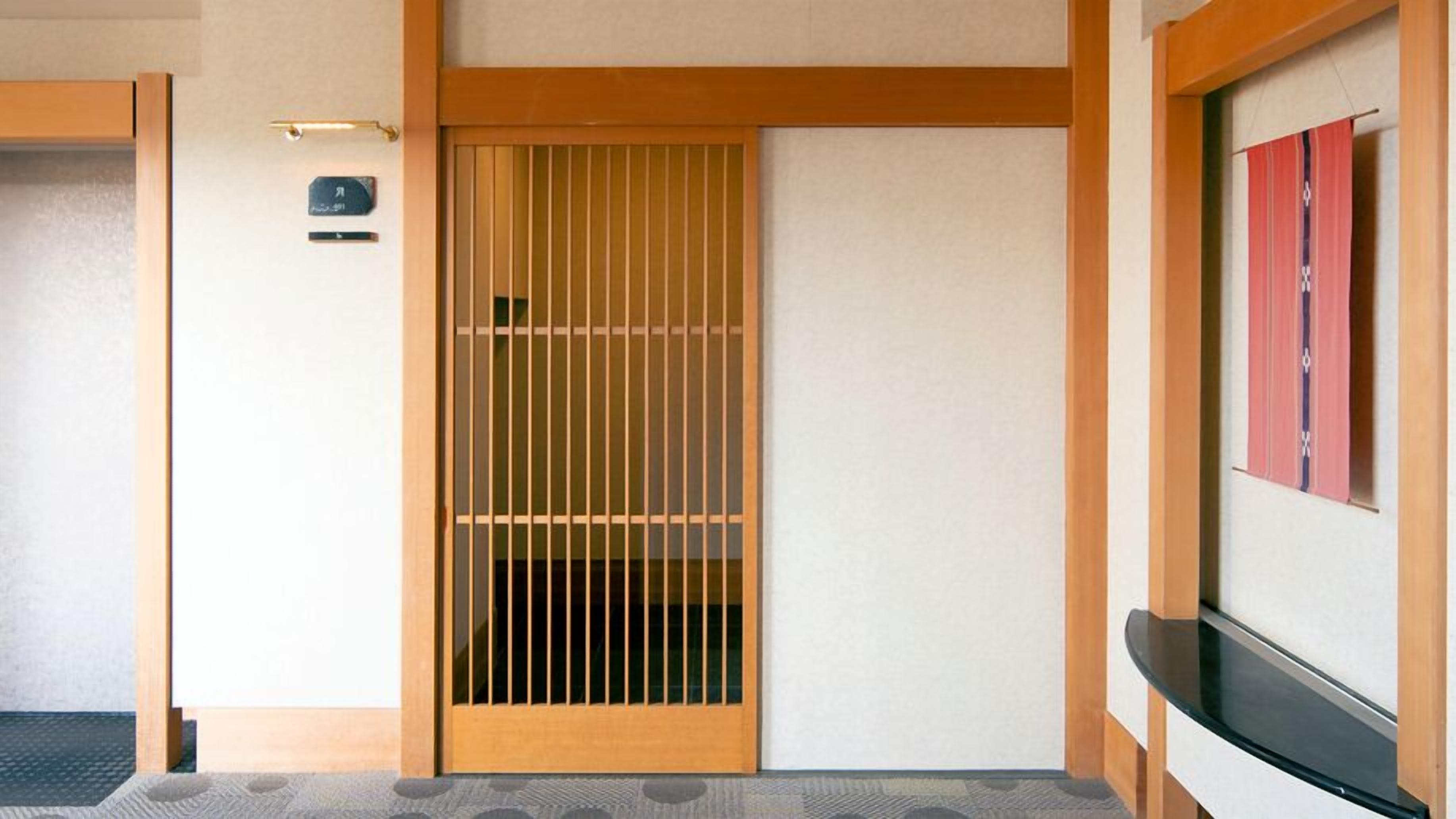 A traditional Japanese room with a sliding door, a small shelf, and a wall-mounted towel rack.