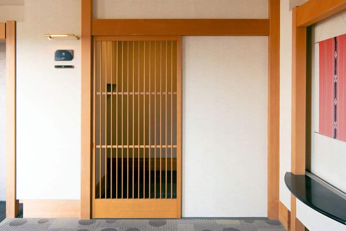 Una habitación japonesa tradicional con un fusuma, un estante pequeño y un perchero de pared.