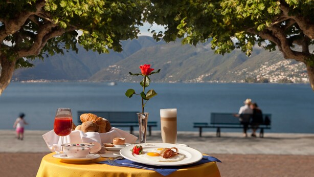 Ein Tisch mit Frühstücksangeboten, einer Rose und Blick auf das Meer und die Berge.