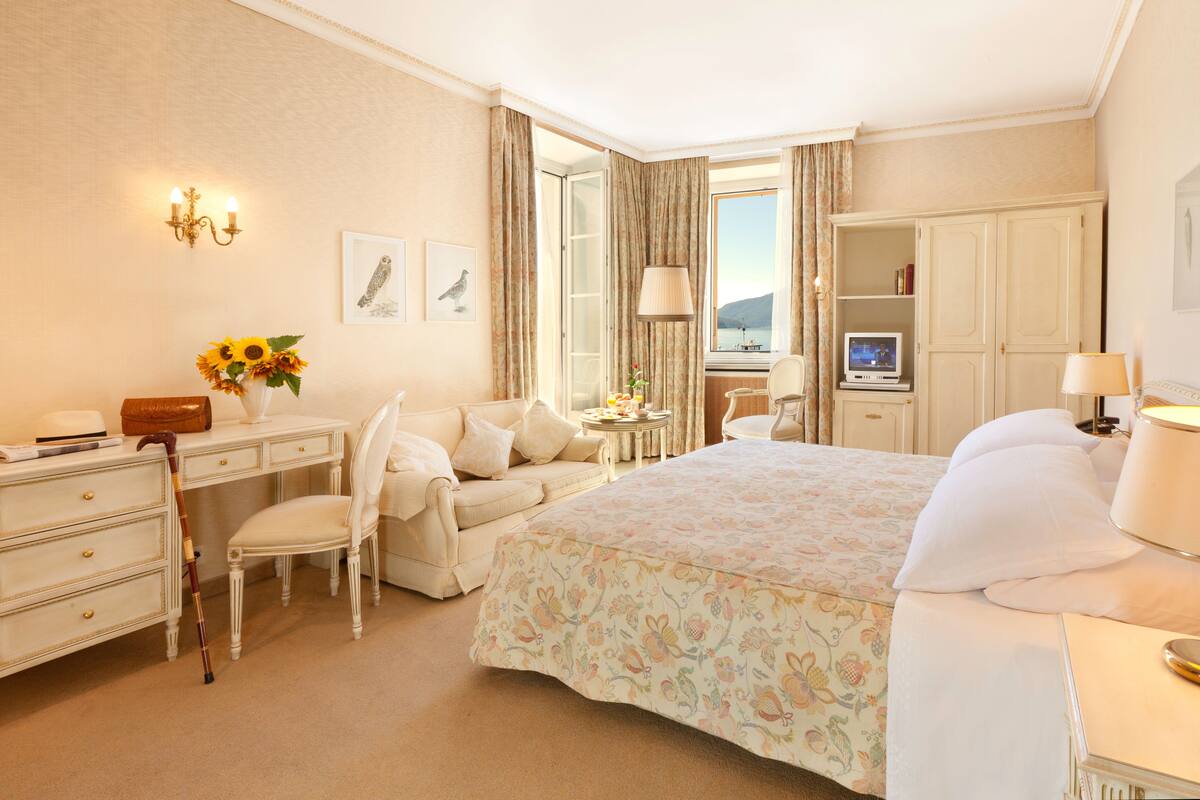 A hotel room with a bed, a desk, a chair, a wardrobe, and a television.