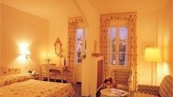 A hotel room with two beds, a desk, a chair, and a small table.