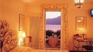 Ein Hotelzimmer mit einem Bett, einem Schreibtisch, einem Stuhl, einer Lampe, einem Fernseher und Blick ins Freie.