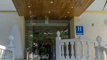 L’entrée d’un hôtel, avec un auvent en bois et une enseigne indiquant « Hôtel Los Jazmines ».