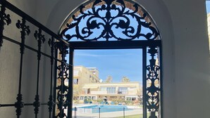 An ornate metal gate leading to a pool area with a clear view of a building in the background. - Hotel Los Jazmines (Torremolinos)