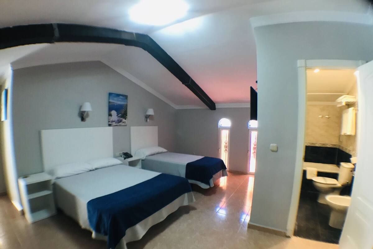 Een hotelkamer met twee bedden, een badkamer en uitzicht op zee.