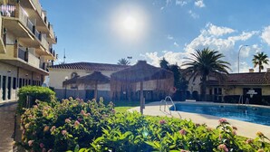 A pool area with a clear sky, a building with balconies, and a reception sign. - Hotel Los Jazmines (Torremolinos)