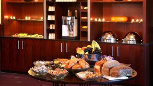 A buffet area with various food items, a coffee machine, and decorative lighting.