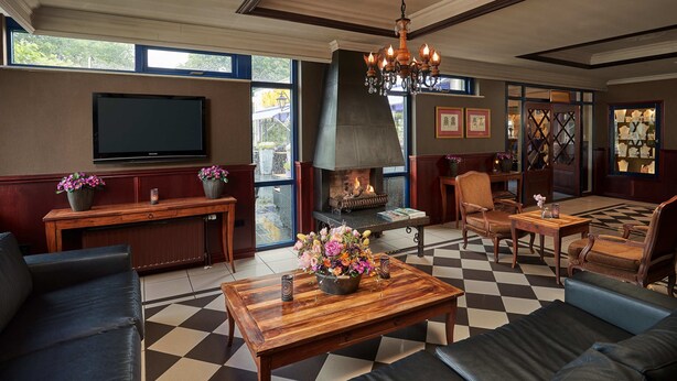 A spacious living room with a fireplace, comfortable seating, a large flat-screen TV, and a chandelier.