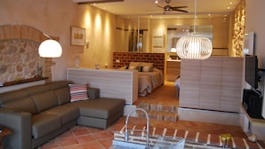 A modern living room with a sofa, a dining area, and a kitchen. - Arianella B&B Penedes (Torrelles de Foix)