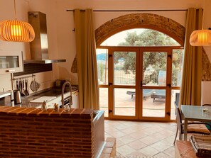 A kitchen with a brick counter, a sink, and a window overlooking a patio. - Arianella B&B Penedes (Torrelles de Foix)