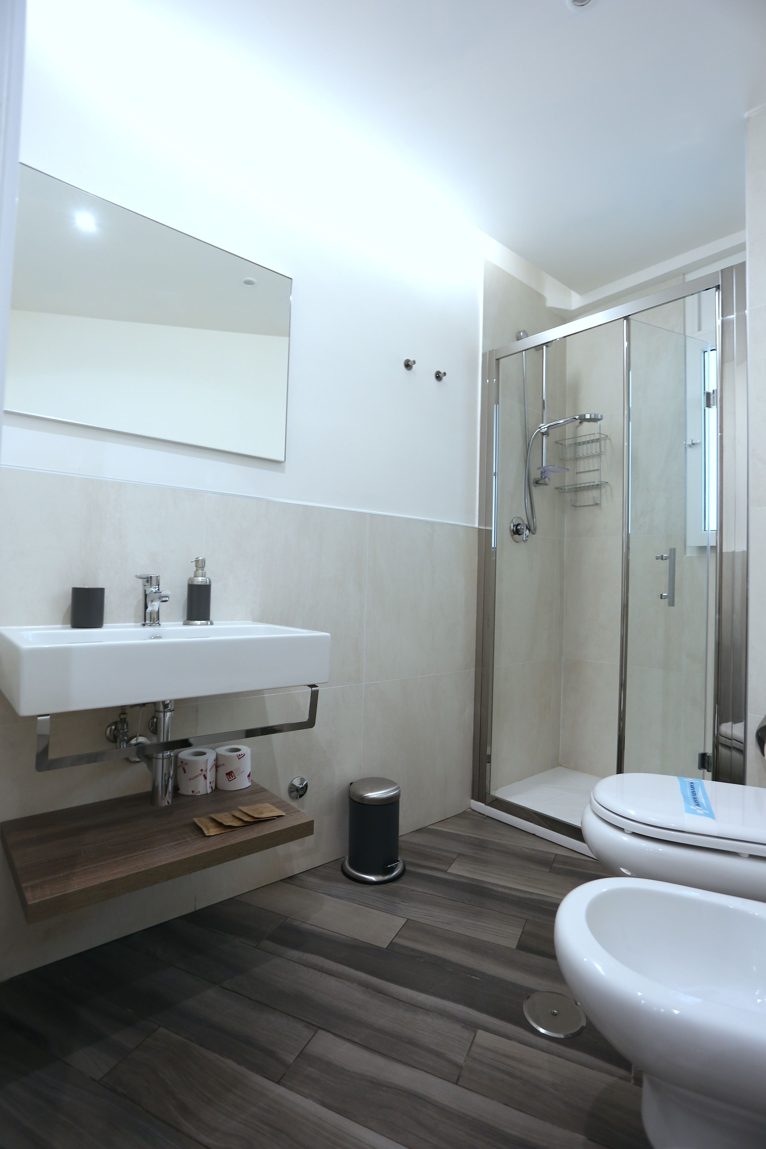 Un baño moderno con lavabo, espejo y retrete blancos.
