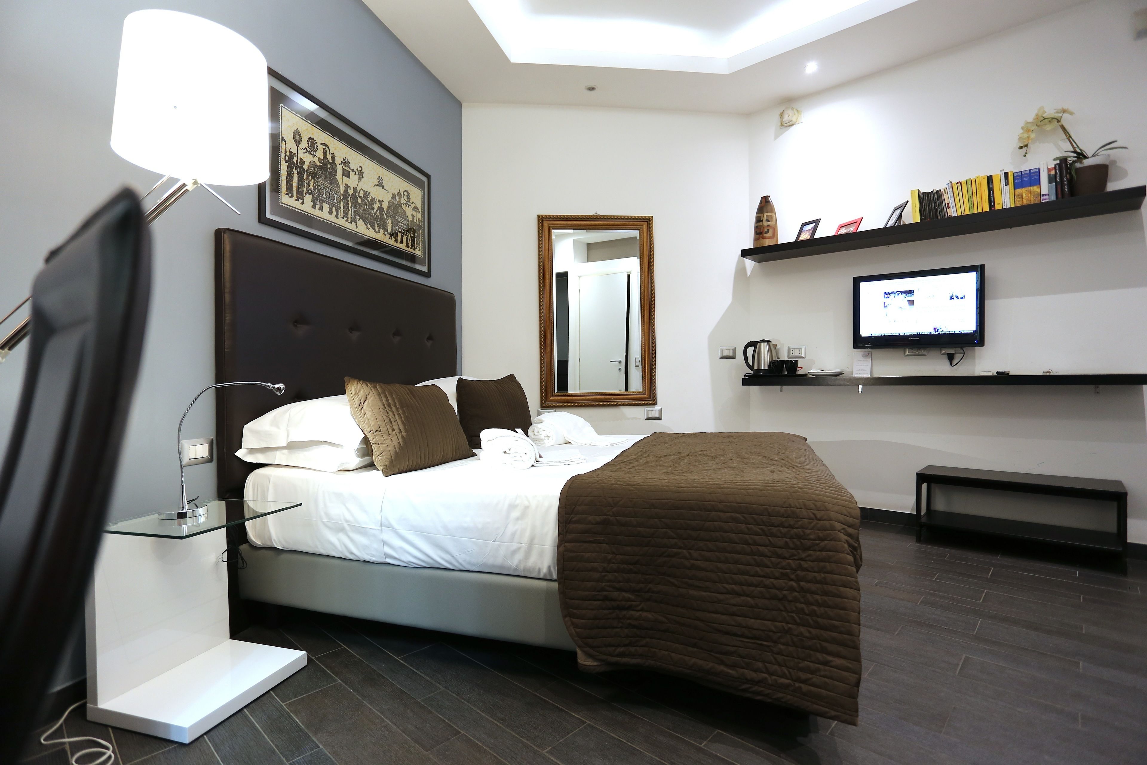 A modern bedroom with a bed, bedside lamp, bedside table, TV, and a bookshelf.