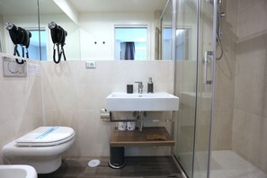 Un baño moderno con inodoro, lavamanos y ducha.