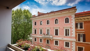 A pink building with multiple windows and a balcony with flowers. - B&B Home 77 (Rome)