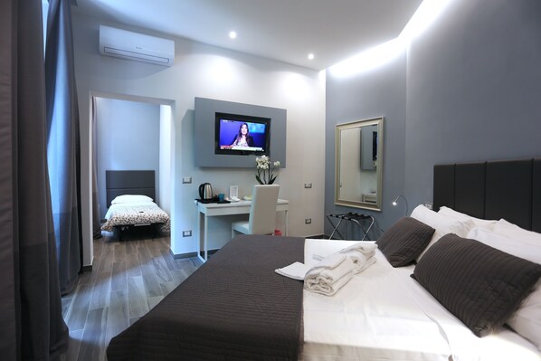 Una habitación de hotel moderna con una cama grande, un escritorio, un televisor de pantalla plana y un espejo.