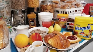 A breakfast table with various food items, including bread, pastries, fruits, and condiments. - B&B Home 77 (Rome)