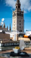 Vista de una torre histórica con detalles arquitectónicos elaborados, cielo azul despejado y edificios modernos al frente.