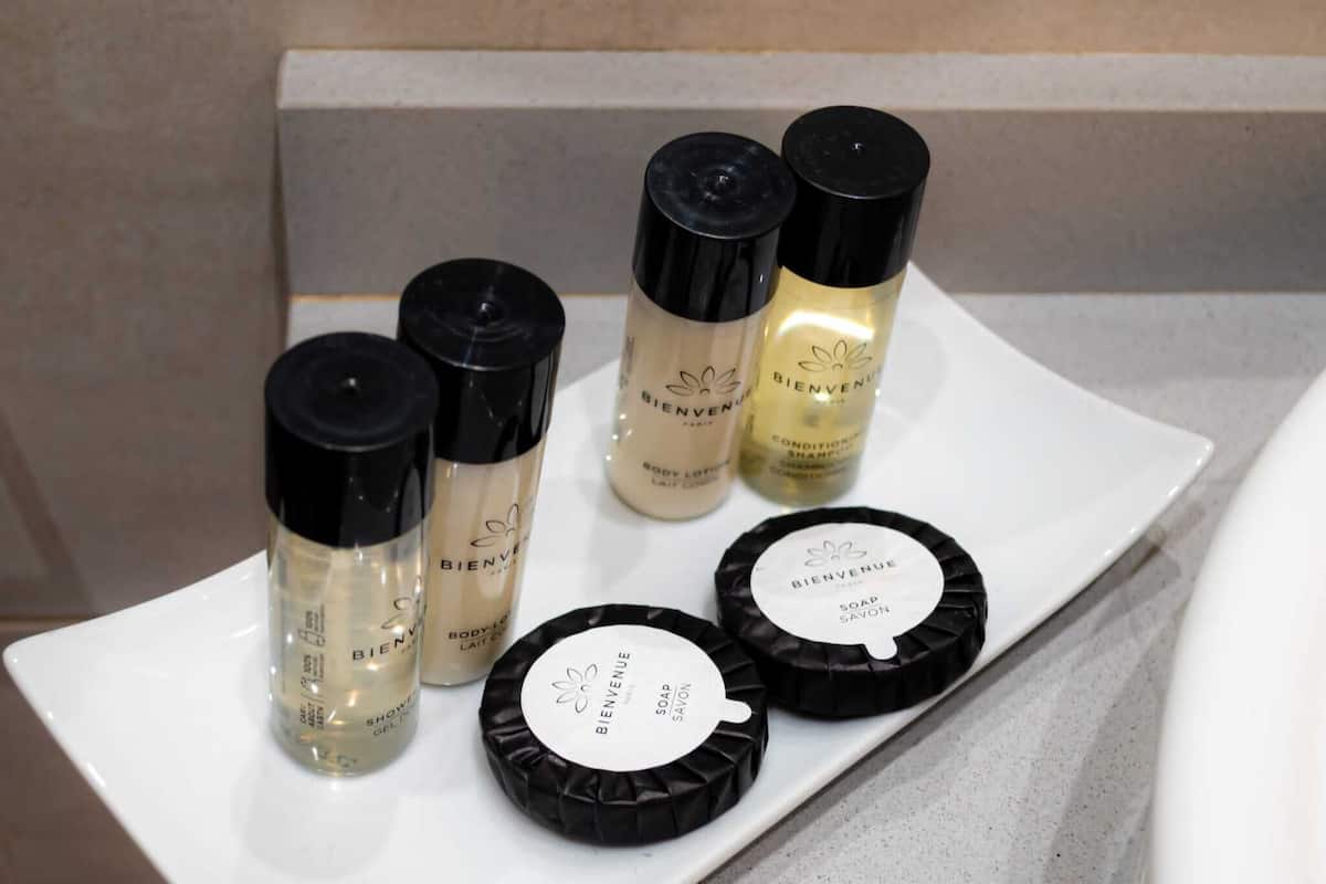 A white rectangular tray with various toiletries including body lotion, shampoo, and soap on a bathroom counter.