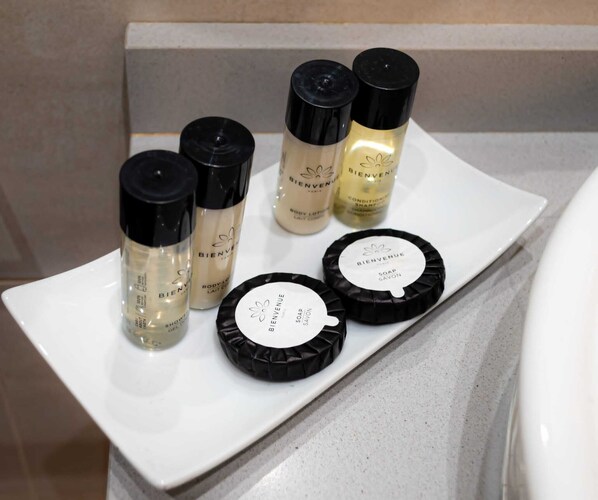 A white rectangular tray with various toiletries including body lotion, shampoo, and soap on a bathroom counter. - Hotel Palacio Alcazar (Seville)