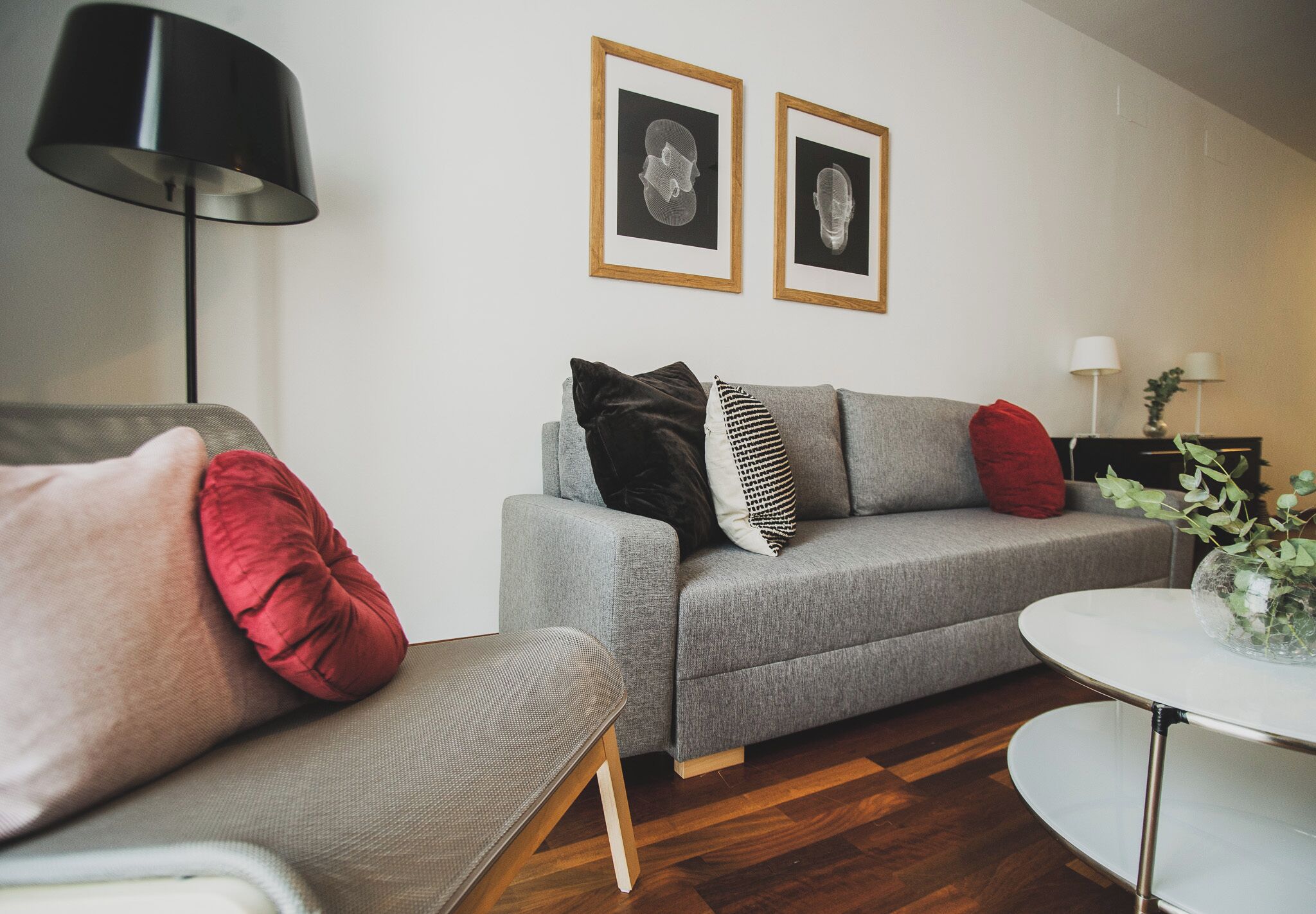 Ein modernes Wohnzimmer mit einem grauen Sofa, einem runden Couchtisch und einer schwarzen Stehlampe.
