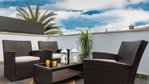 A rooftop patio with wicker furniture, a glass table, and candles. - AZZ Sevilla Torre de la Plata (Seville)