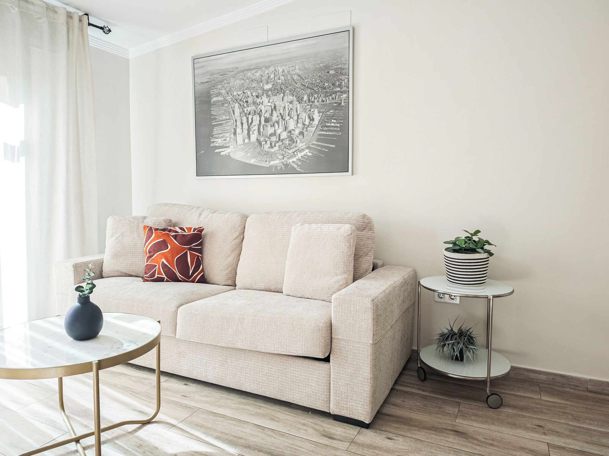 A modern living room with a beige sofa, a round coffee table, and a side table with a plant.