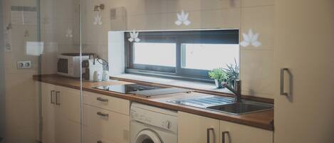 Une cuisine moderne équipée d’un lave-linge intégré, d’un four à micro-ondes et d’une fenêtre située au-dessus de l’évier.