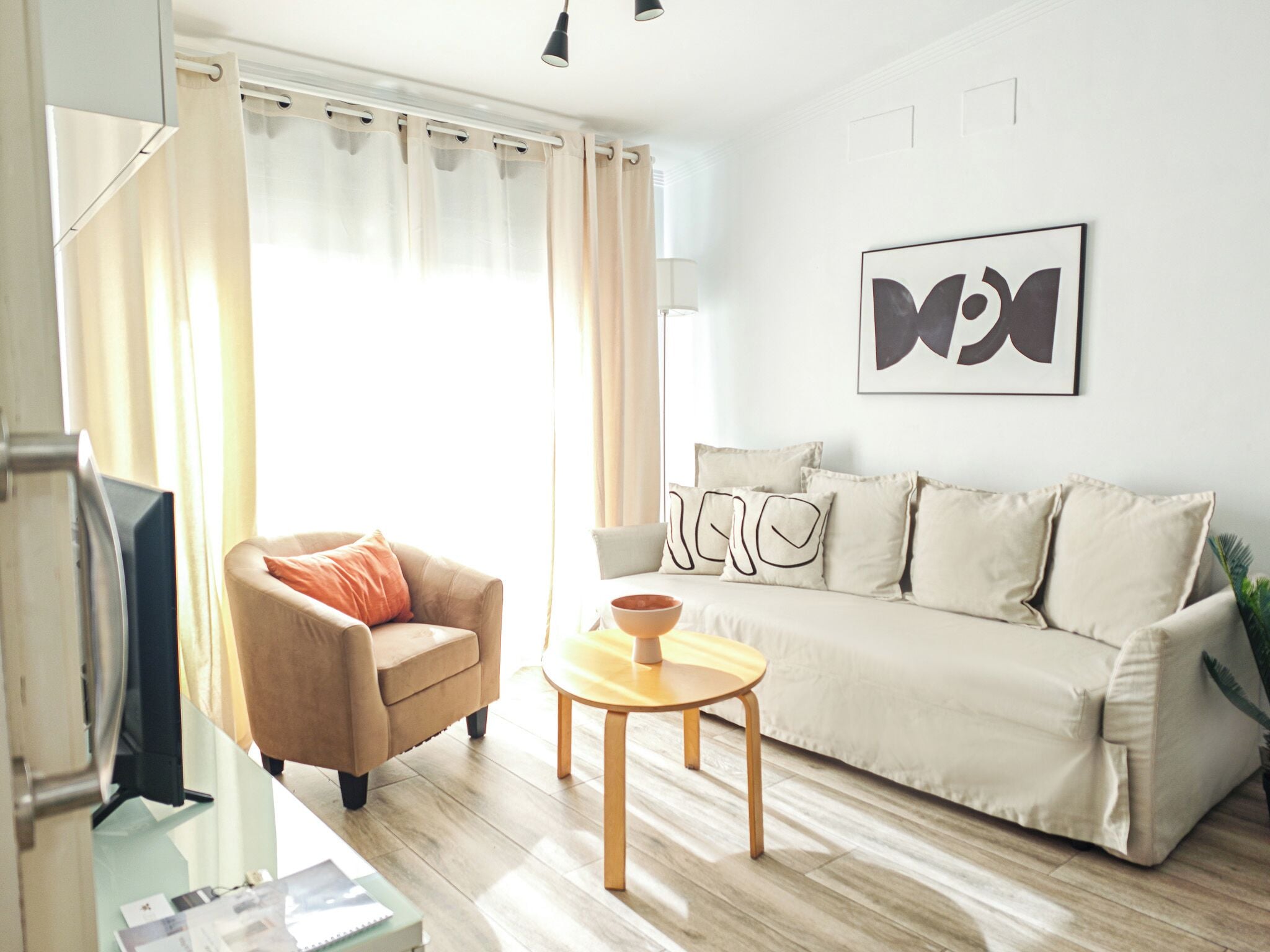 Ein modernes Wohnzimmer mit einem beigen Sofa, einem braunen Sessel und einem Couchtisch aus Holz.