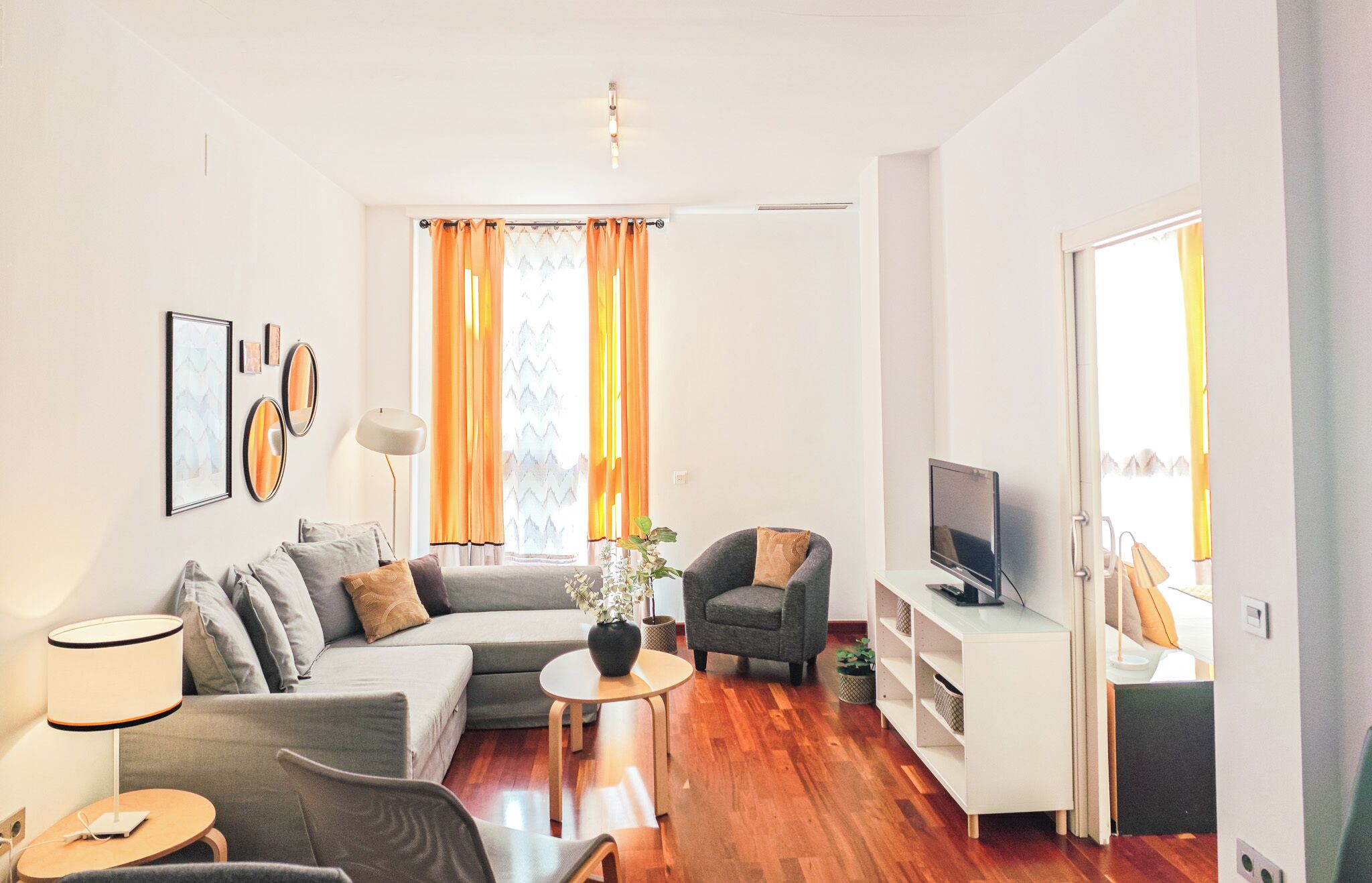 A modern living room with a sofa, armchairs, a coffee table, and a TV.