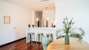 A modern kitchen with a central island, bar stools, and pendant lighting. - AZZ Sevilla Torre de la Plata (Seville)