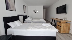 Et moderne hotelværelse med to senge, et skrivebord, et fjernsyn og et spejl på væggen.