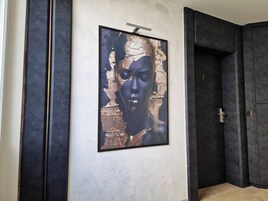 A hallway with a framed artwork on the wall, a door, and a dark-colored wall.