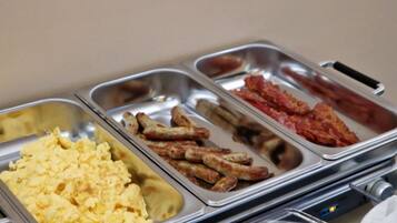 A buffet with scrambled eggs, sausages, and bacon.