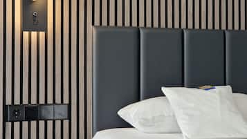Ein modernes Hotelzimmer mit einer Wandpaneele in Holzoptik mit Streifen, einem dunklen Kopfteil und einem Bett mit weißer Bettwäsche und Kissen.