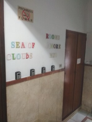Ein Flur mit einem Rauchverbotsschild, einer Wand mit bunten Buchstaben, die "SEA OF CLOUDS" schreiben, und einer Holztür.